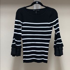 Black and white sweater with bell sleeves.